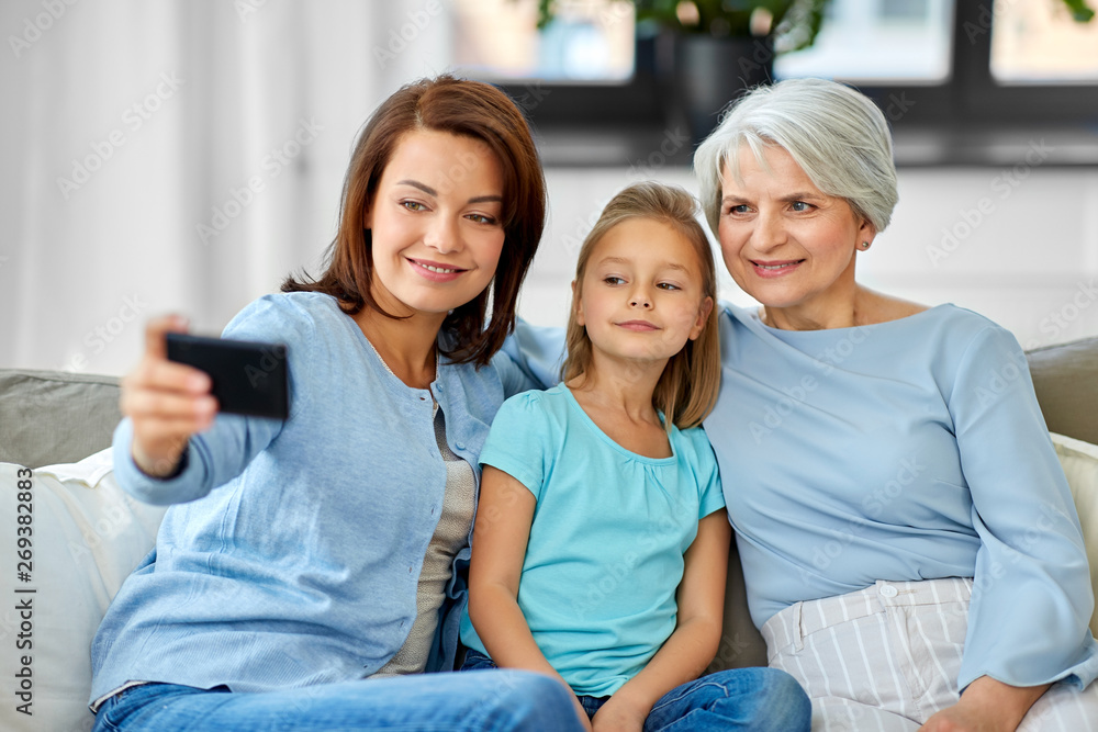 family, generation and technology concept - happy mother, daughter and grandmother taking selfie by smartphone at home family, generation and technology concept - happy mother, daughter and grandmother taking selfie by smartphone at home