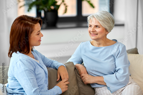 family, generation and people concept - happy smiling senior mother talking to adult daughter at home