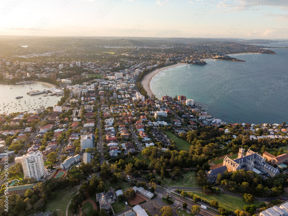 Panoramic evening aerial drone shot of Manly, a beach-side suburb of northern Sydney, in the state of New South Wales, Australia with the historic management college in the foreground.