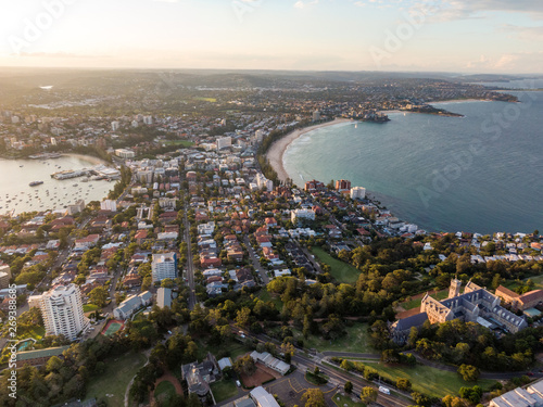 Panoramic evening aerial drone shot of Manly  a beach-side suburb of northern Sydney  in the state of New South Wales  Australia with the historic management college in the foreground.
