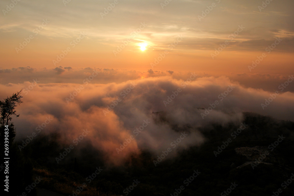 Fototapeta premium Beautiful structure of clouds on sky, mountain landscape with dense fog at sunset on horizon of beauty natural environment. Panorama of amazing sunrise view show sun rays through clouds over mountain.