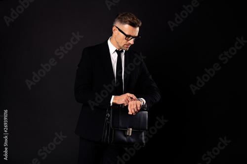 Portrait of his he nice-looking elegant classy chic busy attractive content director partner lawyer attorney economist financier marketer looking at watch isolated over black background