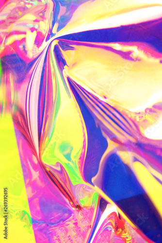 Holographic iridescent surface. Copy space. Bright colorful hologram background. Wrinkled abstract texture with multiple colors. Neon surface.