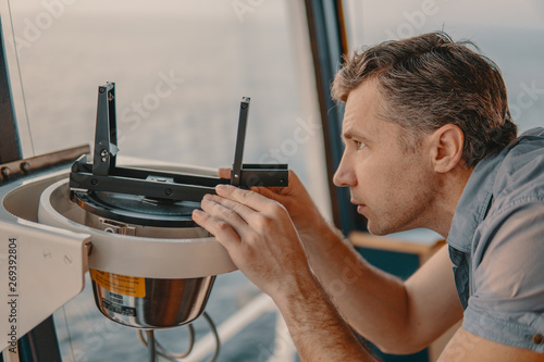 Quadro em tela Marine deck officer taking magnetic compass error onboard of vessel at open sea