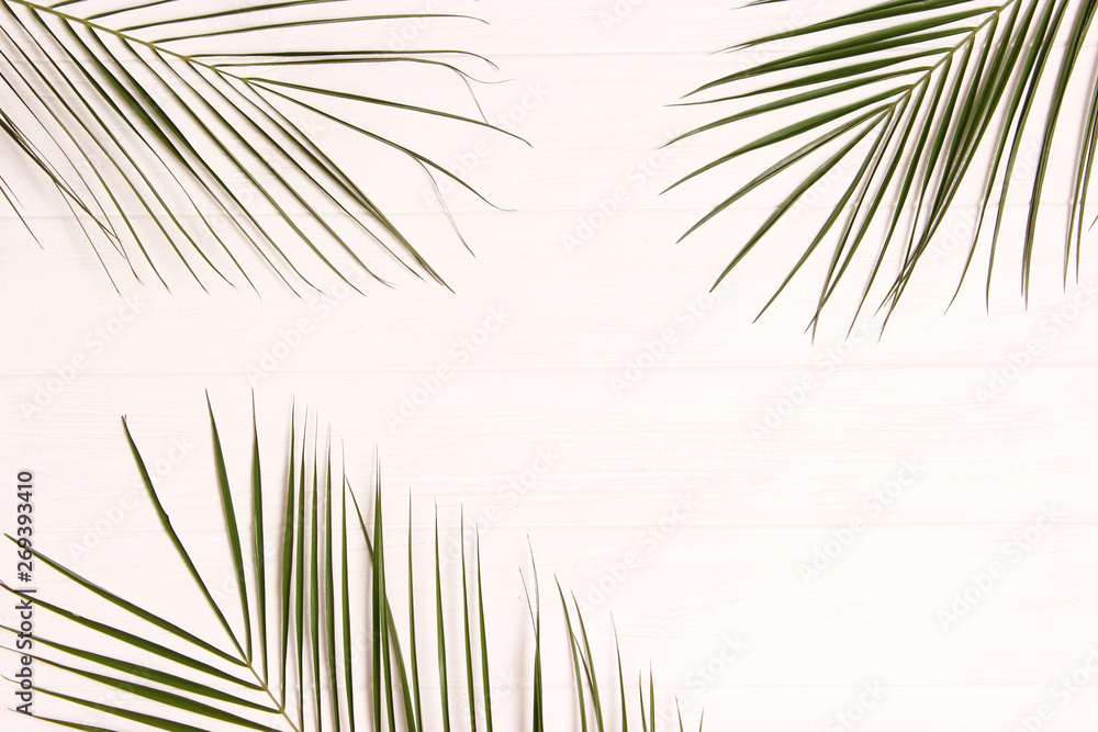 Fototapeta premium palm leaves on a wooden background with free space for text. a draft for a design. minimalism, creativity. flatlay