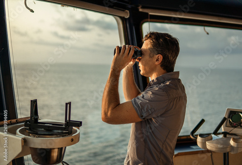 Navigational officer lookout on navigation watch looking through binoculars. Marine industry. COLREG collision regulations