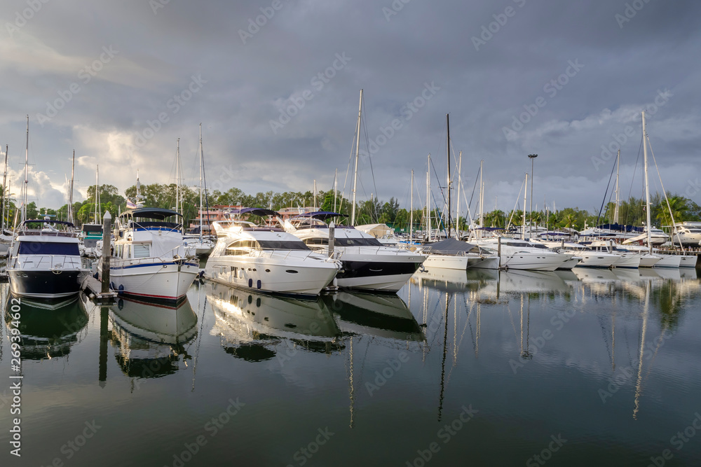Boats and yachts in a marina with dark cloud on sky. 