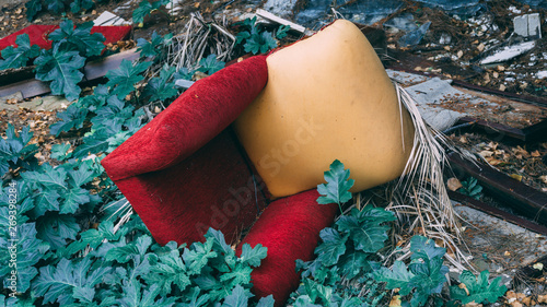 Comfortable old armchair dumped on the ground. Colorful thrown away furniture in the nature. photo