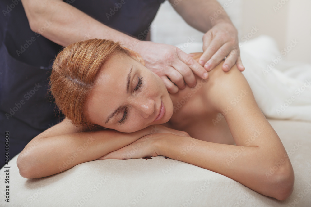 Charming red haired woman enjoying full body massage by professional therapist. Attractive relaxed female getting massage at spa center, copy space Charming red haired woman enjoying full body massage by professional therapist. Attractive relaxed female getting massage at spa center, copy space