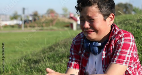 Cute caucasian preteen boy crying in the park