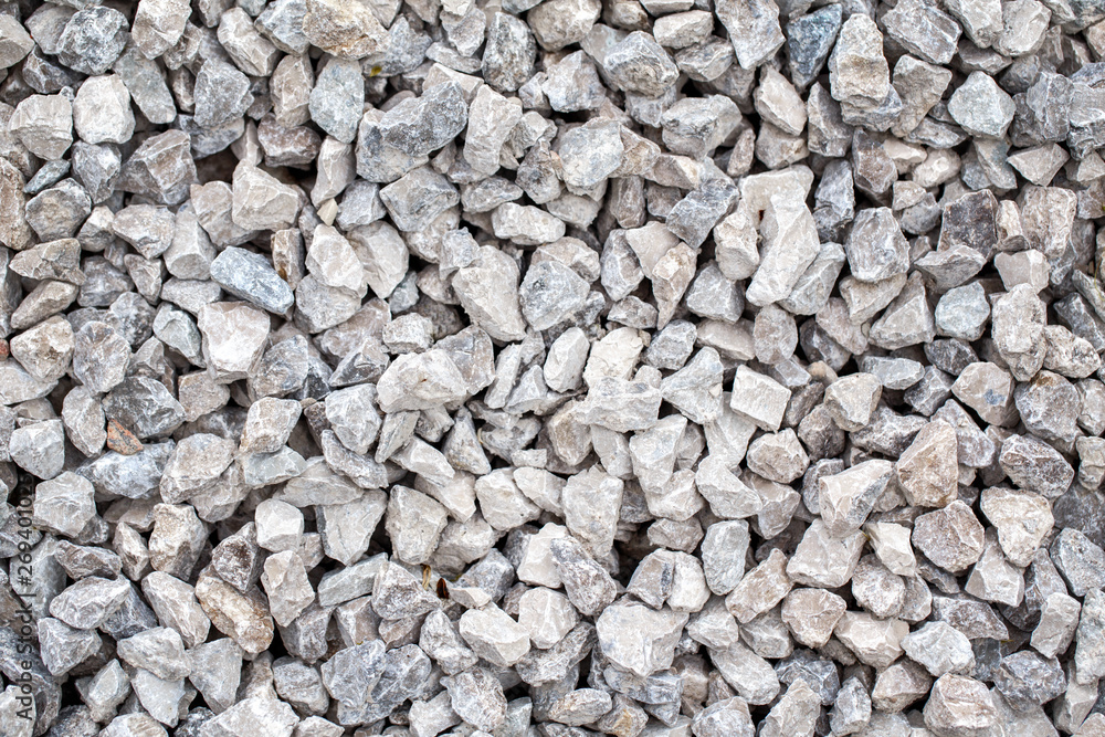 Closeup of small little grey beige blue broken crushed stones rocks lying on ground. Natural environmental background texture. Garden rubble macadam top overhead view. Closeup of small little grey beige blue broken crushed stones rocks lying on ground. Natural environmental background texture. Garden rubble macadam top overhead view.