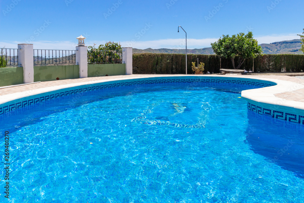 A beautiful luxury swimming pool at a villa in the holiday destination of Malaga in Spain under blue sky in summer