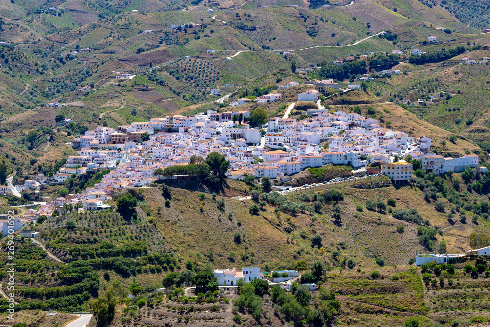 The town of Almáchar, in the province of Málaga, part of Andalusia in southern Spain shot from the mountains above, showing the traditional white washed buildings and tile roofs.