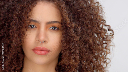 hair blowing closeup portrait of mixed race model with freckles watching to the camera directly