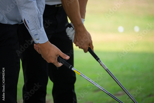 The hands of two golfers who are holding golf clubs.