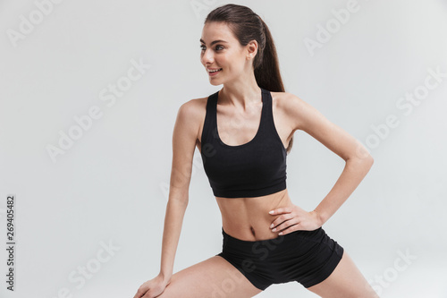 Beautiful young sport fitness woman make exercises isolated over grey wall background.