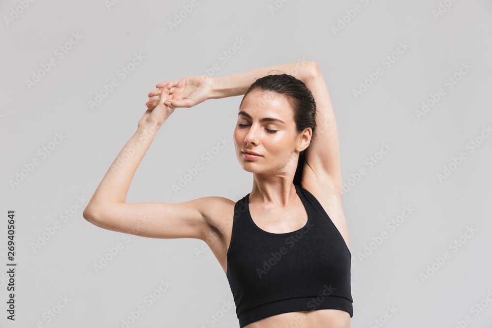 Beautiful young sport fitness woman make exercises isolated over grey wall background. Beautiful young sport fitness woman make exercises isolated over grey wall background.