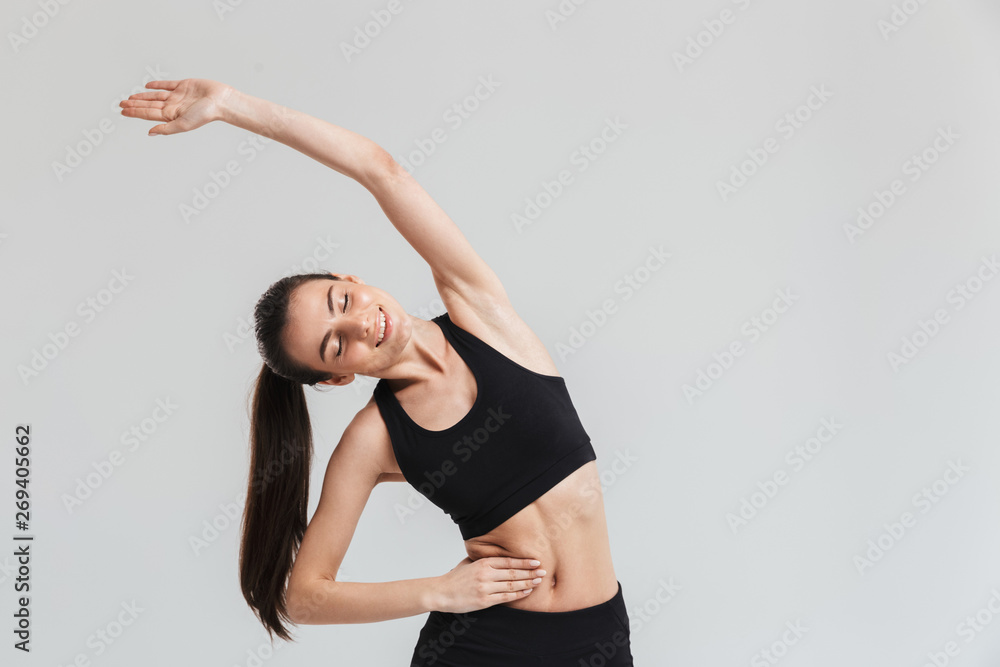 Beautiful young sport fitness woman make exercises isolated over grey wall background. Beautiful young sport fitness woman make exercises isolated over grey wall background.