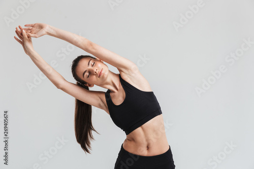 Beautiful young sport fitness woman make exercises isolated over grey wall background.