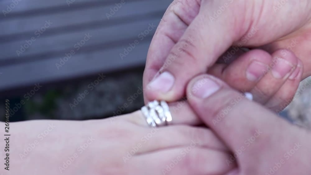 Close-up of a man putting diamond and silver ring on woman's finger. Close-up of a man putting diamond and silver ring on woman's finger.