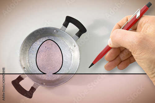 A hand draws the outline of a fried egg above an old aluminum pan - concept image photo