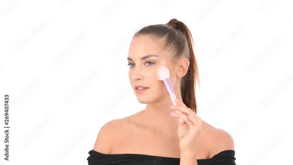 Beauty concept. A beautiful girl is using a brush to paint her face. Beauty concept. A beautiful girl is using a brush to paint her face.