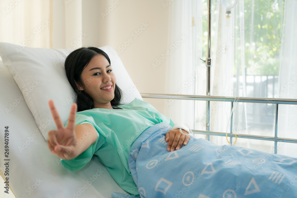 Young Asian patient woman lying at hospital bed with saline drip