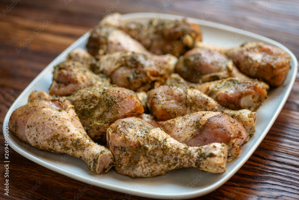 Chicken drumsticks on white dish, wooden background Chicken drumsticks on white dish, wooden background