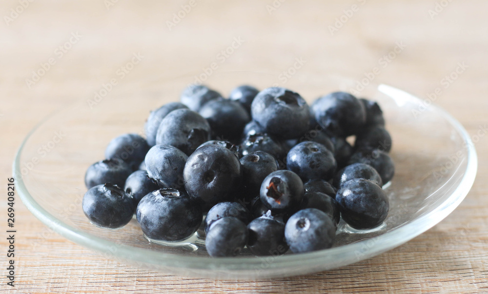 Blueberry in glass plate on wooden background. Blueberry in glass plate on wooden background.