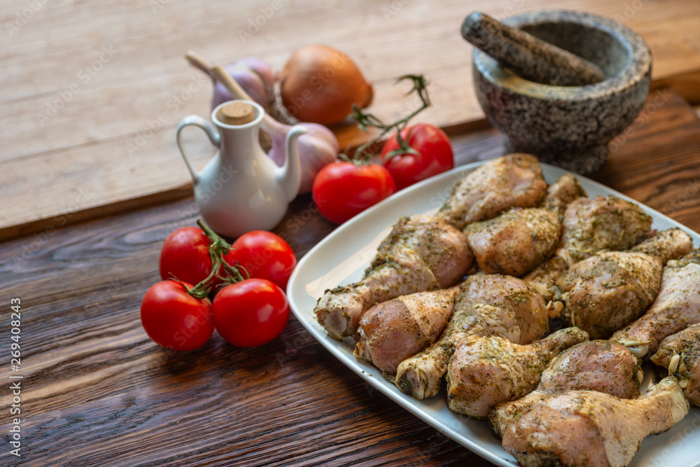 Raw chicken legs with herbs and spices on white dish. Raw chicken legs with herbs and spices on white dish.