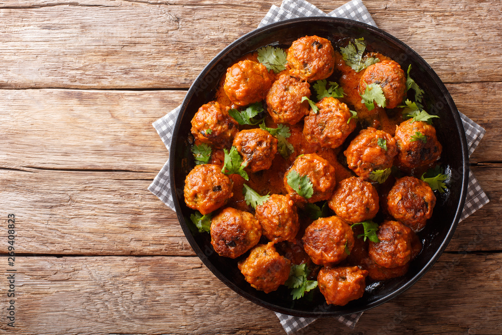 Indonesian chicken meatballs in coconut curry sauce with cilantro closeup on a plate. horizontal top view Indonesian chicken meatballs in coconut curry sauce with cilantro closeup on a plate. horizontal top view