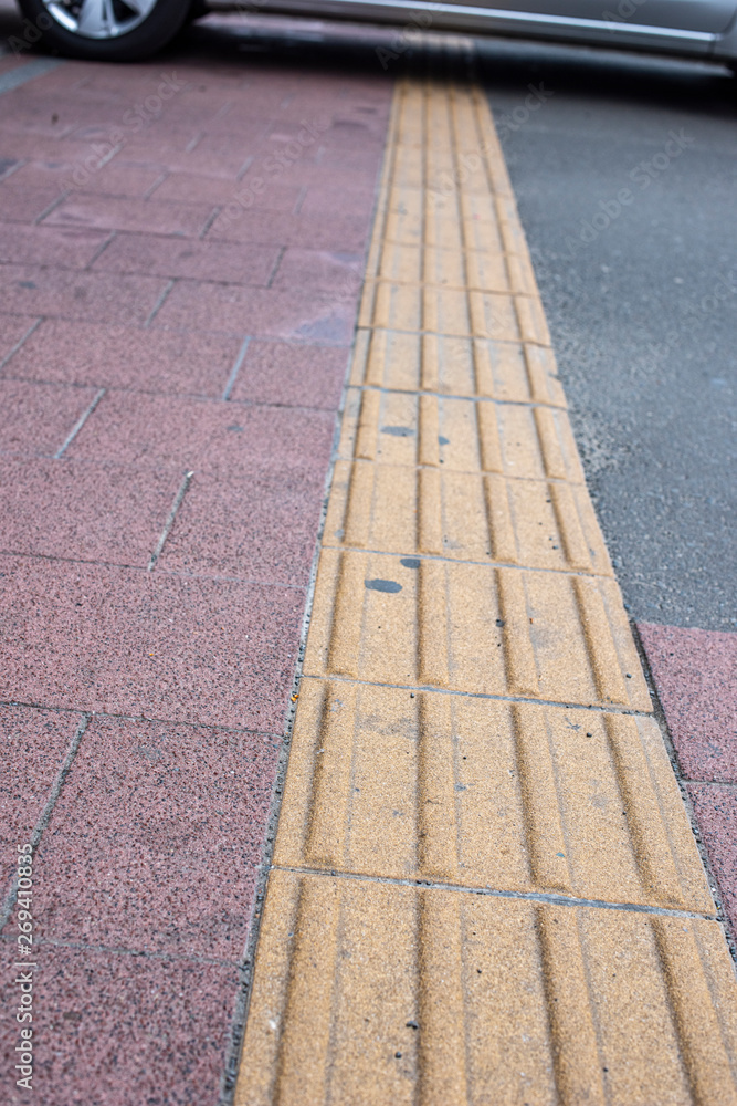Bright yellow tactile footpath for people who have visually impaired on the walkway. This path will guide blind people walking safely in a busy city.