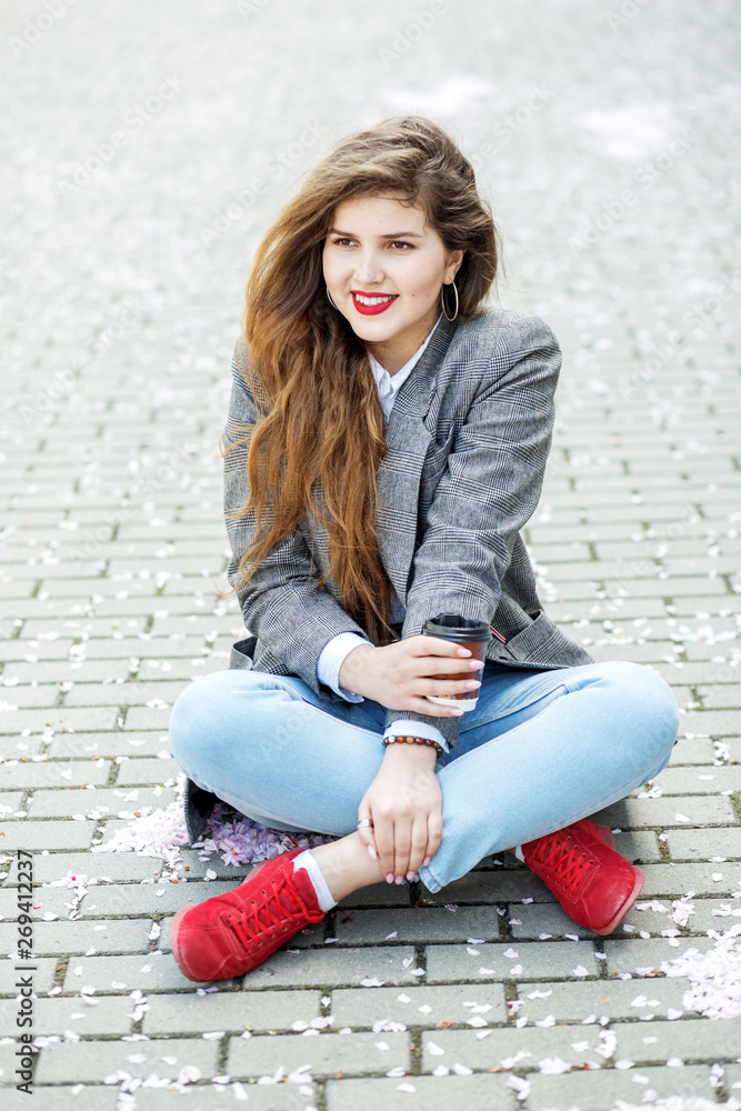 Happy girl sitting on the floor with coffee. Concept of lifestyle, urban, leisure, students Happy girl sitting on the floor with coffee. Concept of lifestyle, urban, leisure, students