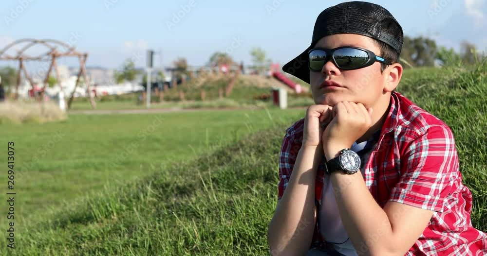 Sad preteen boy sitting in the park alone Sad preteen boy sitting in the park alone