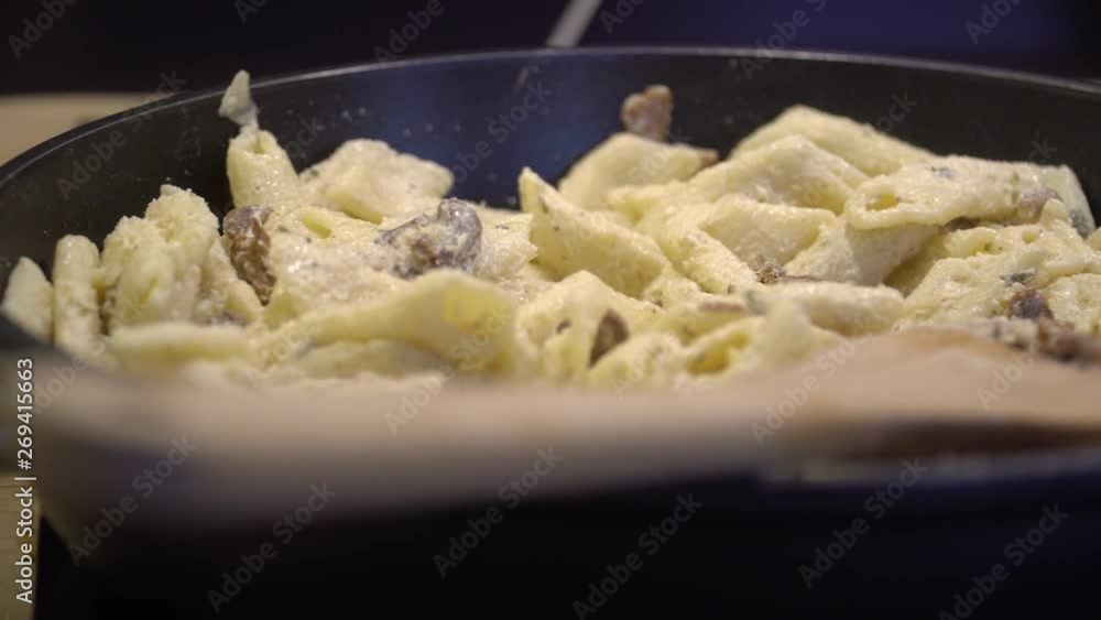 Pasta with cheese and meat on cast iron pan. Cooking macaroni dinner. Pasta spaghetti with white sauce and chicken breast. Pasta with cheese and meat on cast iron pan. Cooking macaroni dinner. Pasta spaghetti with white sauce and chicken breast.