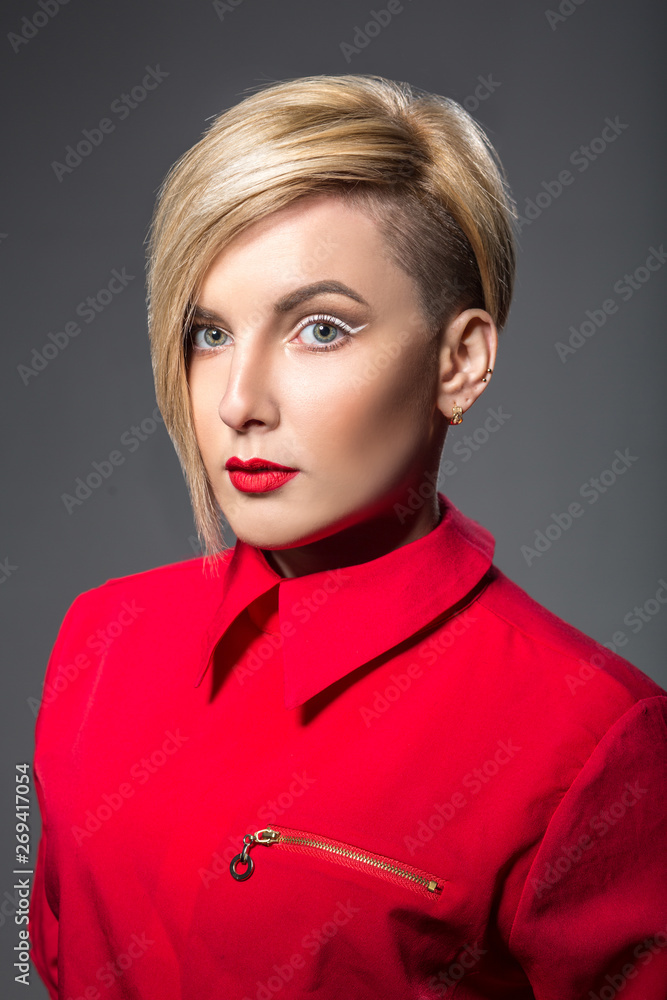 Young woman with short trendy haircut and bright eyeliner makeup over grey background Young woman with short trendy haircut and bright eyeliner makeup over grey background
