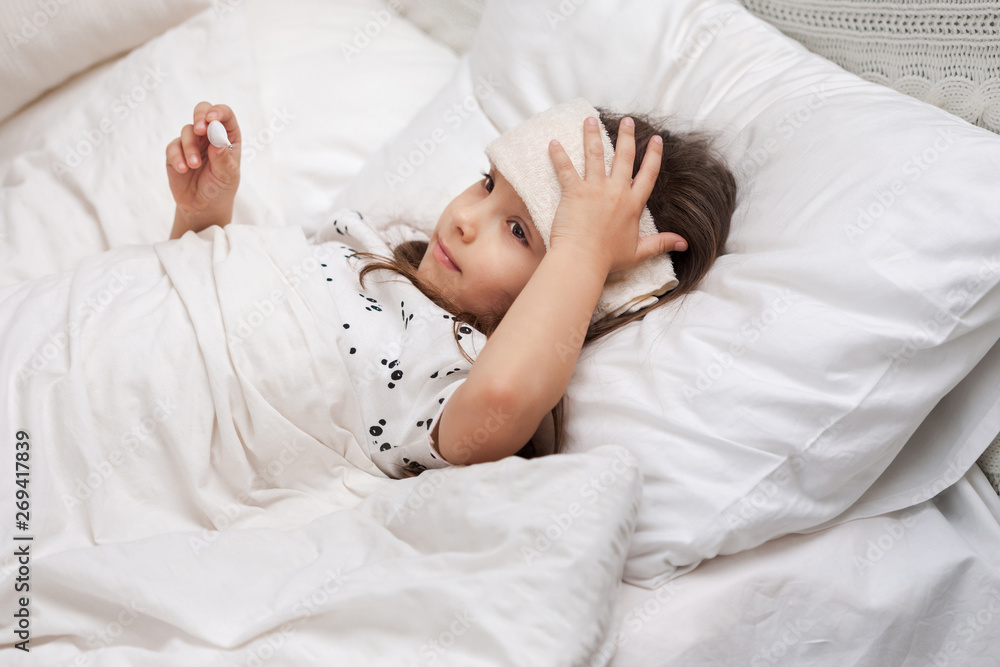 Sick little child girl lying in bed with thermometer. Cold flu season Sick little child girl lying in bed with thermometer. Cold flu season