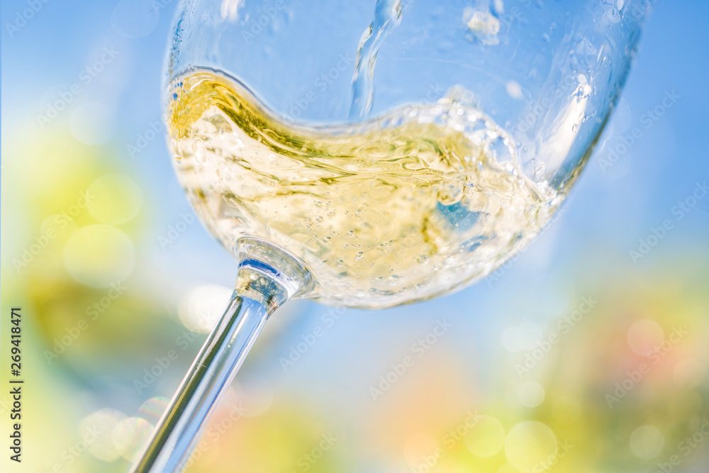 Colorful close-up of pouring white wine in a glass