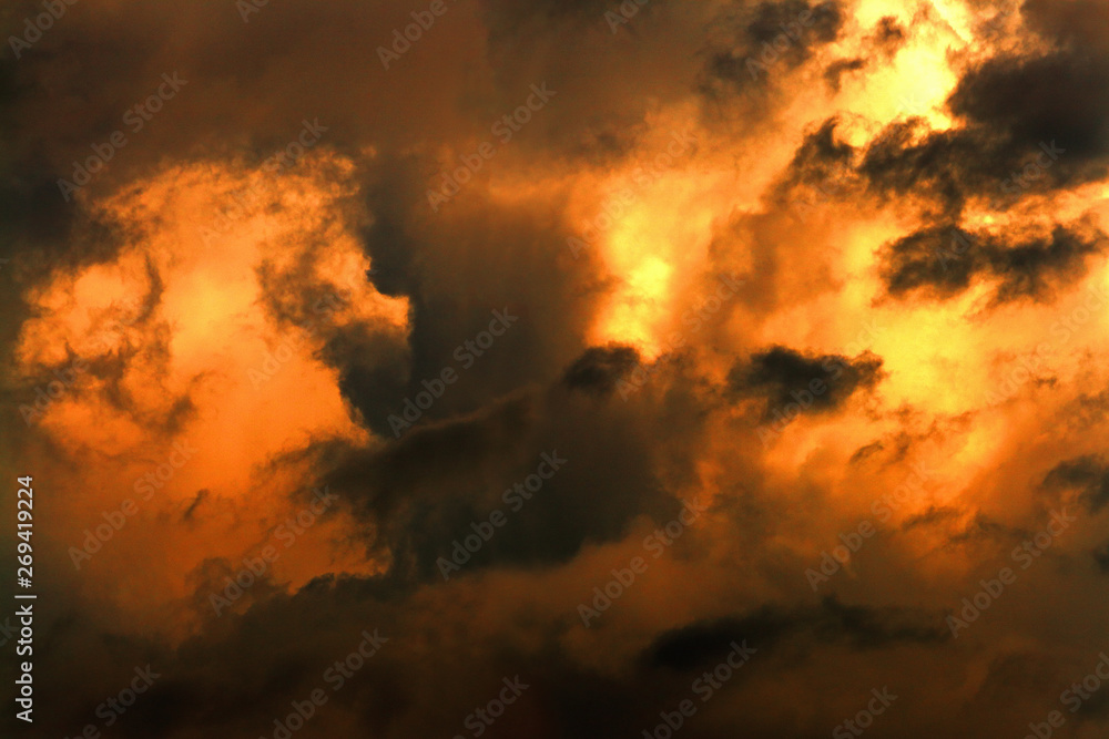Dark clouds illuminated by the bright light of the sun. Apocalyptic dramatic background.