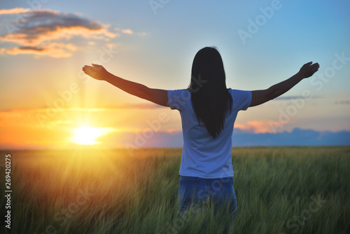 Woman feeling free in a beautiful natural setting, in what field at sunset
