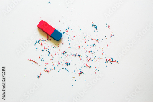 Pink and blue eraser and it’s shavings sitting on a clean white sheet of paper with copy space – Small office supply for correcting errors – Concept image for erasing mistakes and editing photo
