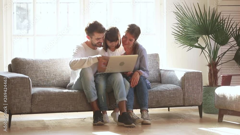 Happy parents with kid daughter using laptop in living room Happy parents with kid daughter using laptop in living room