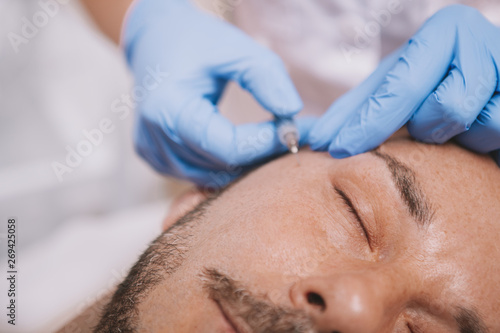 Cropped close up of a mature man getting anti-wrinkle treatment at cosmetology clinic. Aged man getting face filler injections at medical clinic