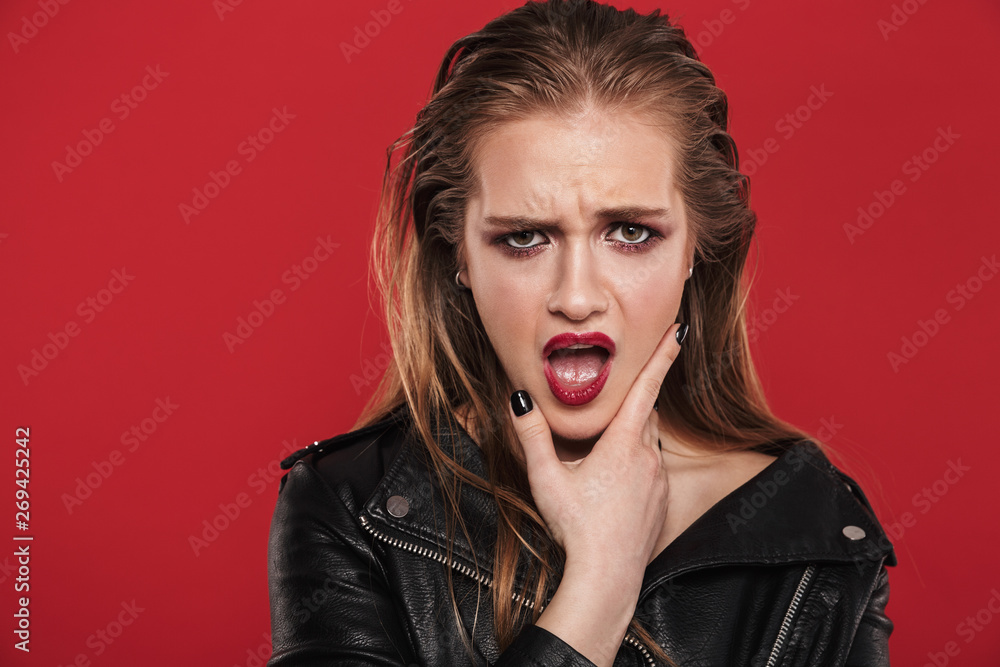 Beautiful young sad emotional woman with bright makeup red lipstick posing isolated over red wall background. Beautiful young sad emotional woman with bright makeup red lipstick posing isolated over red wall background.