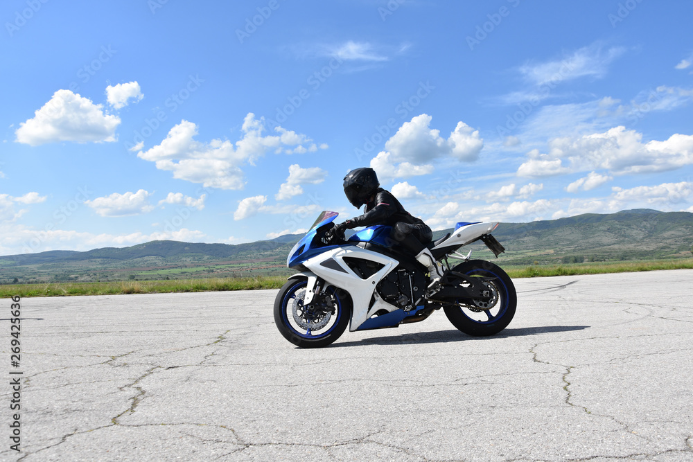 Young woman motorcyclist speeding on tarmac racetrack - former airport runway near the town of Dupnitsa, Bulgaria