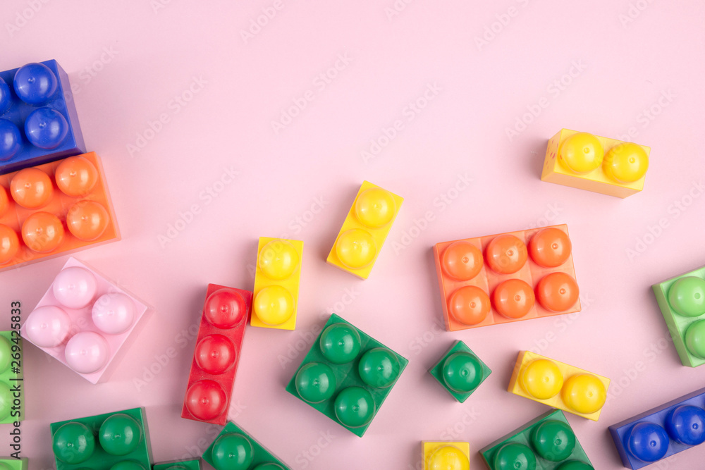 Kids toys background with colorful blocks laying on the pink table. Flat lay with copy space for text.