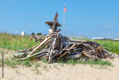 Beach driftwood sculpture erected on sand dune.