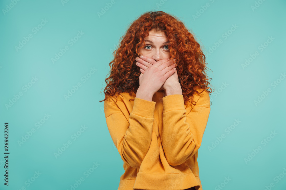 Photo of pretty woman 20s with curly ginger hair looking at camera and covering her mouth Photo of pretty woman 20s with curly ginger hair looking at camera and covering her mouth