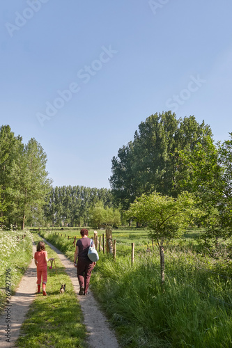 Mother and daughter walking on country road with a small dog