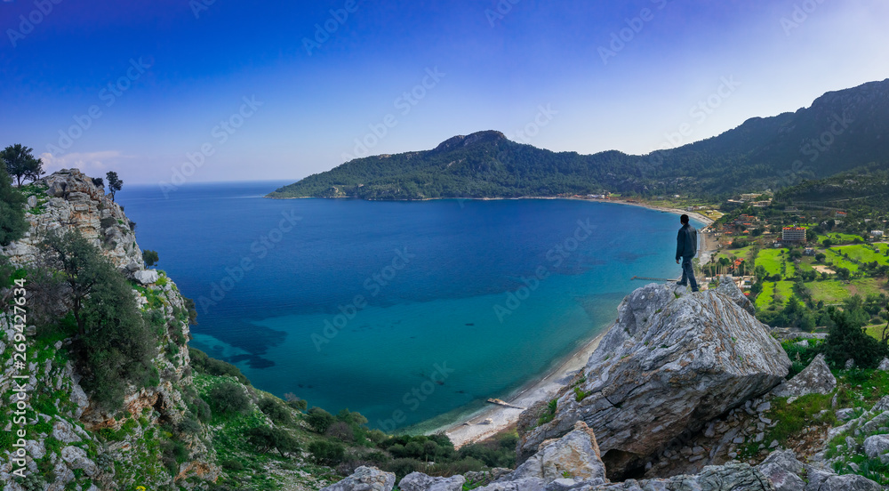 The man watching the panoramic view of marmaris, on the edge of the cliff. Kumlubuk, Marmaris, Turkey. Amos Ancient city. Amazing coastline. Holiday, travel and tourism concept.